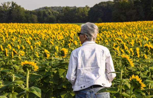 Pierrette Darlington, CFO owner of Brothers Dog Food walking thru a sunflower field in Kansas City, Missouri