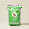 Green bag of Brothers Complete Ultra Premium Dog Food on a beige background